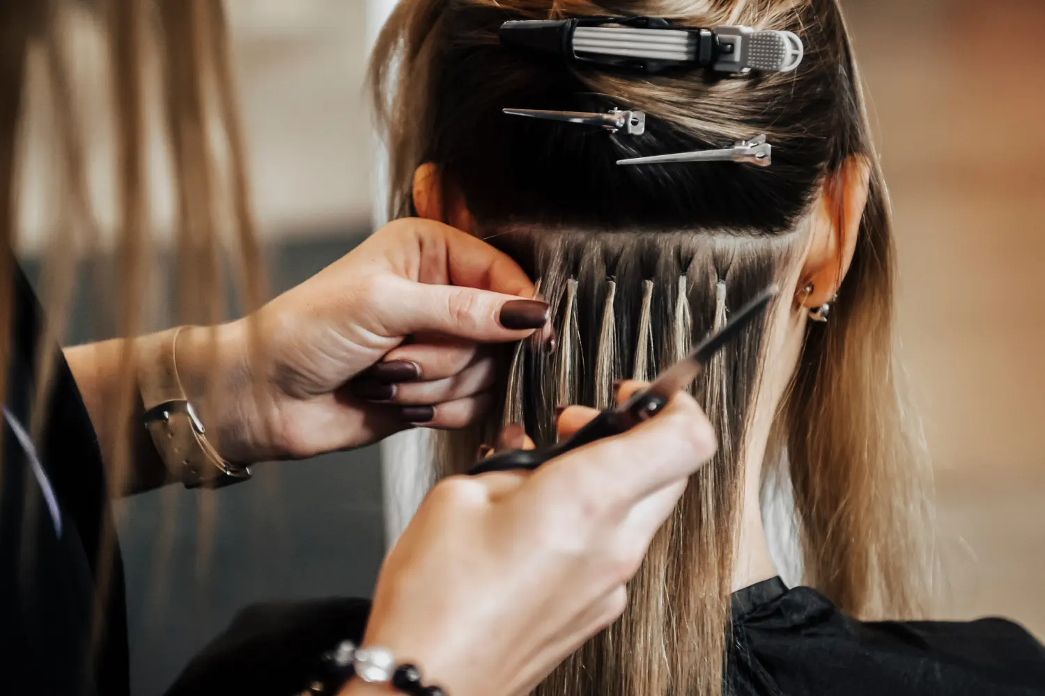 Die Friseurin macht Haarverlängerungen an einer blonden Frau in einem Schönheitssalon. Professionelles Haarkonzept